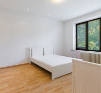 A bright bedroom in a family house with large windows, beds, and parquet flooring.