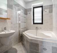 Bathroom with a corner bathtub, sink, and windows, Family house.