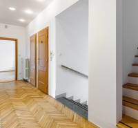 A hallway with parquet flooring, stairs, and wooden doors in a family house.