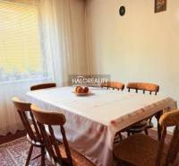 Dining room with a wooden table and chairs, decorated with curtains and a cutlery picture.