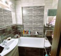 Bathroom in a 2-room apartment with a bathtub, sink, and a shelf with towels.