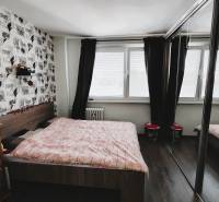Bedroom in a 2-room apartment with a large window, sliding mirror doors, and a decorative wall.