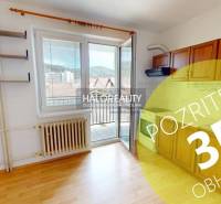 Studio apartment with a practical kitchen, wooden cabinets, and a large window to let in natural light.