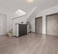 Hallway with stairs and three doors in a 4-room apartment with a chest of drawers and a coat rack.