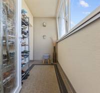 Balcony in a 4-room apartment with a shoe cabinet, carpet, glazing, open window.