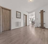 Hallway of a 4-room apartment with wooden doors, a mirror, and a view into the kitchen.