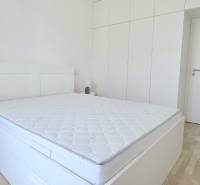 Bedroom in a 2-room apartment with white furniture and a built-in wardrobe.