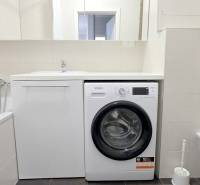 Bathroom in a 2-room apartment with a bathtub, washing machine, and toilet.