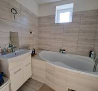 A bathroom in a family house with a bathtub and a sink in light shades.