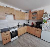 A kitchen in a family house with light wooden cabinets, a white refrigerator, and an electric stove.