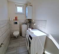 Laundry room in a family house with a washing machine, boiler, and toilet.