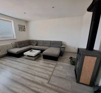 Living room with a corner sofa, fireplace stove, and a table in a family house.