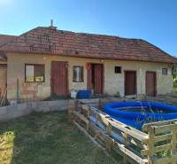 Family house in Kmeťovo with an extension, inflatable pool, and simple wooden fence.
