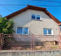 A family house in Kmeťovo with a white facade and a metal fence.