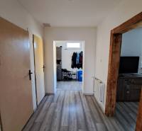 A hallway in a family house with laminate flooring, wooden door frames, and a shoe storage.