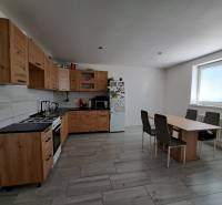 A kitchen in a family house with wooden cabinets, a dining table, and appliances.