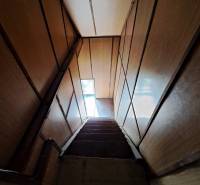 A staircase with wooden walls leading to a narrow window in a family house.