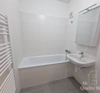A bathroom in a 4-room apartment with a bathtub, a sink, and white tiles.