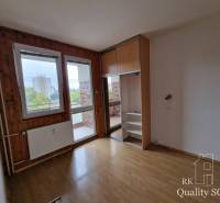 An empty room in a 4-room apartment with wooden panels and a view of the balcony.