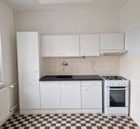A kitchen in a 4-room apartment with white cabinets and tiled flooring.