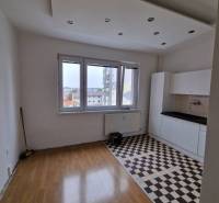 Living space in a 4-room apartment with patterned flooring and a kitchen unit.