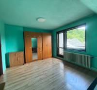 A room in a family house with a wooden floor, a wardrobe, and a balcony window.
