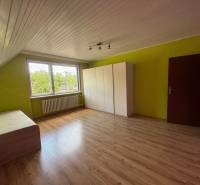 A room in a family house with laminate flooring, colorful walls, a bed, and a wardrobe.