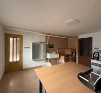 Interior of a family house with a wooden table, chairs, a tiled stove, and doors.