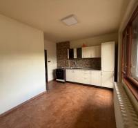 A kitchen in a family house with white cabinets, a stove, and a window with a radiator.