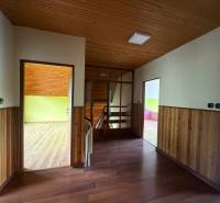 A hallway in a family house with wooden paneling and a view of colorful rooms.