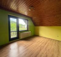 Green room in the attic of a family house with a view of nature through a large window.