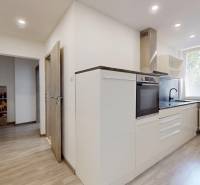 A kitchen in a 2-room apartment with white cabinets and a built-in oven.