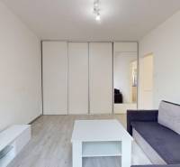 A bright living room with a sofa, a table, and a built-in wardrobe in a 2-room apartment.