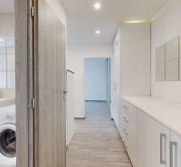 Hallway of a 2-room apartment with white furniture, built-in wardrobe, and a bathroom with a washing machine.