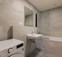Bathroom with a bathtub and a washing machine in a 3-room apartment, light tiles and a sink.