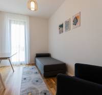 A room in a 3-room apartment with a lounger, a table, a chair, and wall decoration.