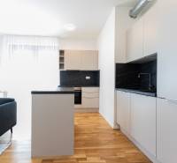 A kitchen in a 3-room apartment with gray furniture, wooden flooring, and a dining table.