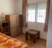 A room in a family house with wooden furniture and a bedspread.