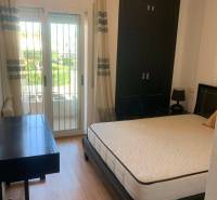 Bedroom in a family house with a bed, a desk, and access to a balcony.