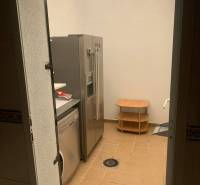 Laundry room in a family house with a refrigerator, washing machine, and a small table on a tiled floor.