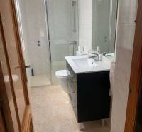 Bathroom in a family house with a sink, shower, and light-colored tiles.
