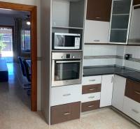 A kitchen in a family house with a microwave, an oven, and glass cabinet doors.