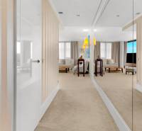 A hallway with striped wallpaper and a mirror leads to the living room of a three-room apartment.