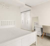 A bright bedroom with white furniture and a desk in a three-room apartment.