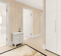 A hallway with a white wardrobe, a table, and a view of the water surface in a 3-room apartment.