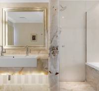A bathroom with a sink, shower, and bathtub in a 3-room apartment with bright marble decor.