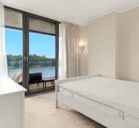 A room in a 3-room apartment with a view of the river, bright interior, bed by the window.