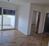 Interior of a 4-room apartment with wooden flooring and large windows.