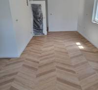 Interior of a 4-room apartment with new wooden flooring and lighting from the window.