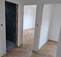 A hallway in a 4-room apartment with a wooden floor and open doors.